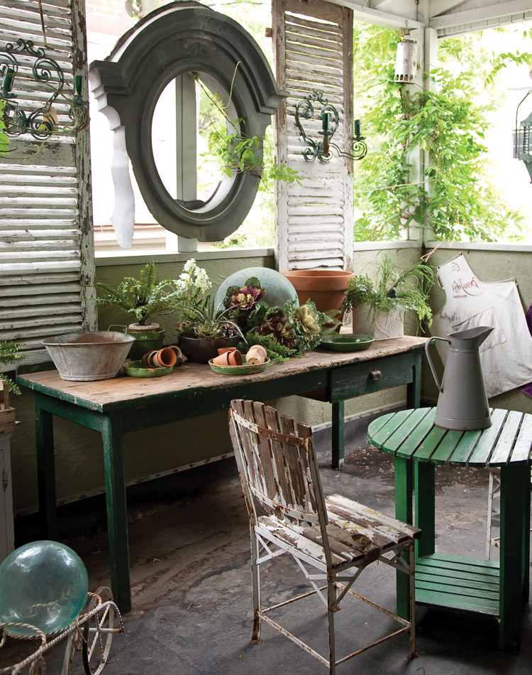 An antique zinc oval window frame from an old French château, a pair of distressed wooden shutters, and a primitive garden table.