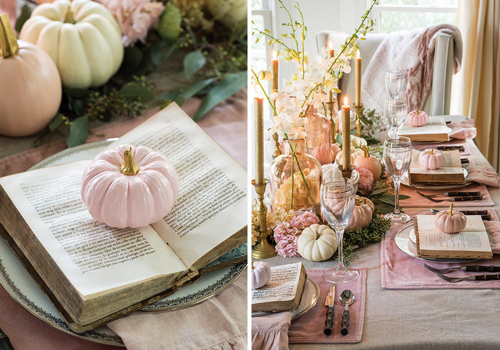 A feminine tablescape is decorated with gold candles, velvet pink placemats, antique books, and pale pink pumpkins.