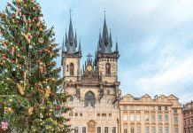 A massive outdoor Christmas tree stands outside the Church of Our Lady before Tyn, the spires of which rise above the square.