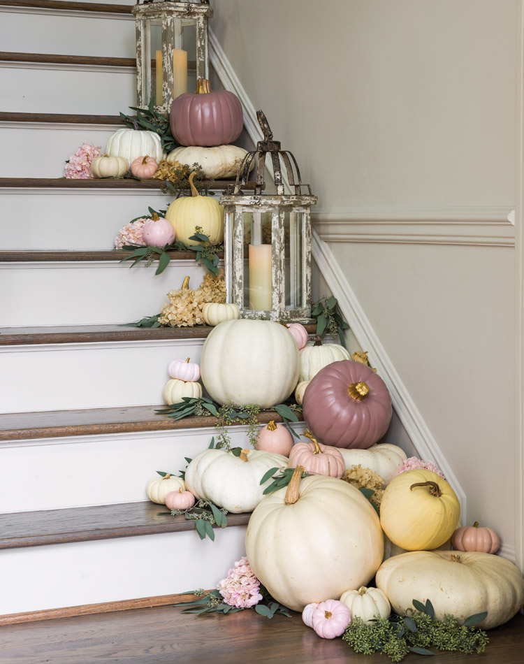 Pink and white pumpkins are pleasingly arranged on the side of a staircase.