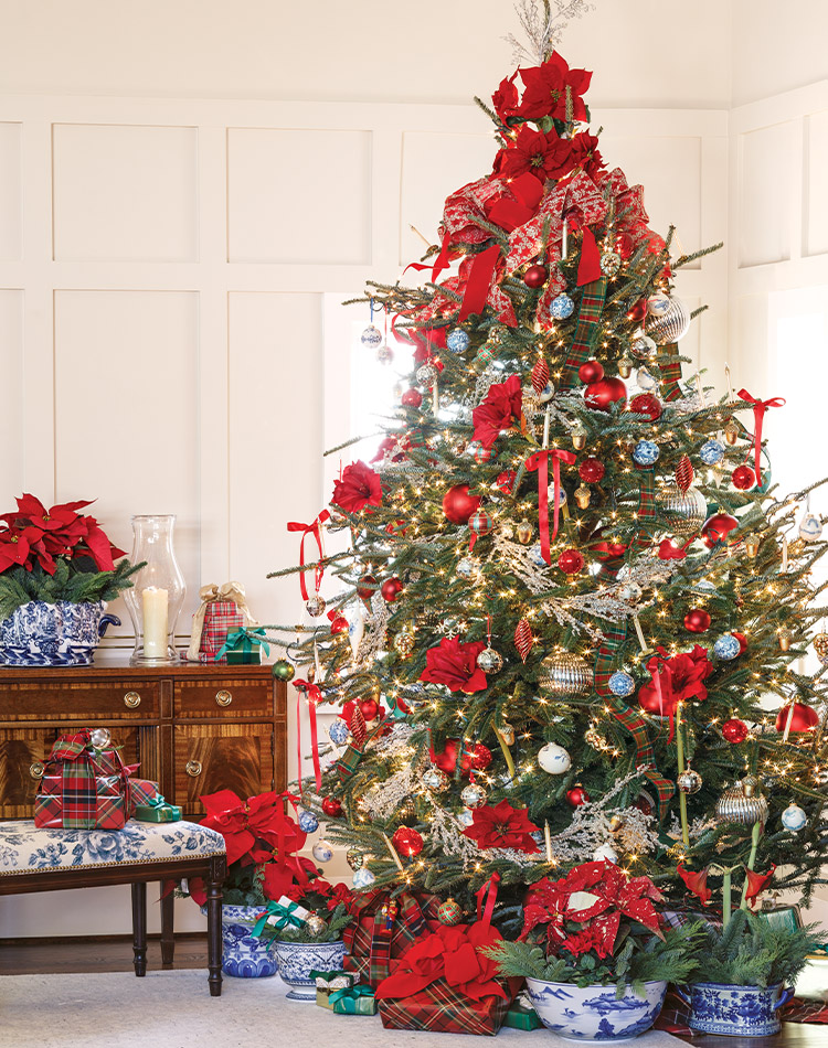 Crowned with poinsettias and kissed with balls of silver, this evergreen is painted with vibrant shades of red ribbon and blue-and-white accents.