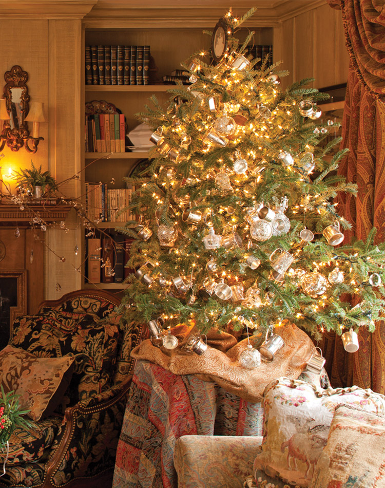 Displayed atop a table in a cozy living room, this diminutive tree sparkles with yellow lights and silver cups.