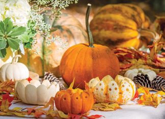 Orange and white pumpkins, some cut into votive candle holders, adorn the table.