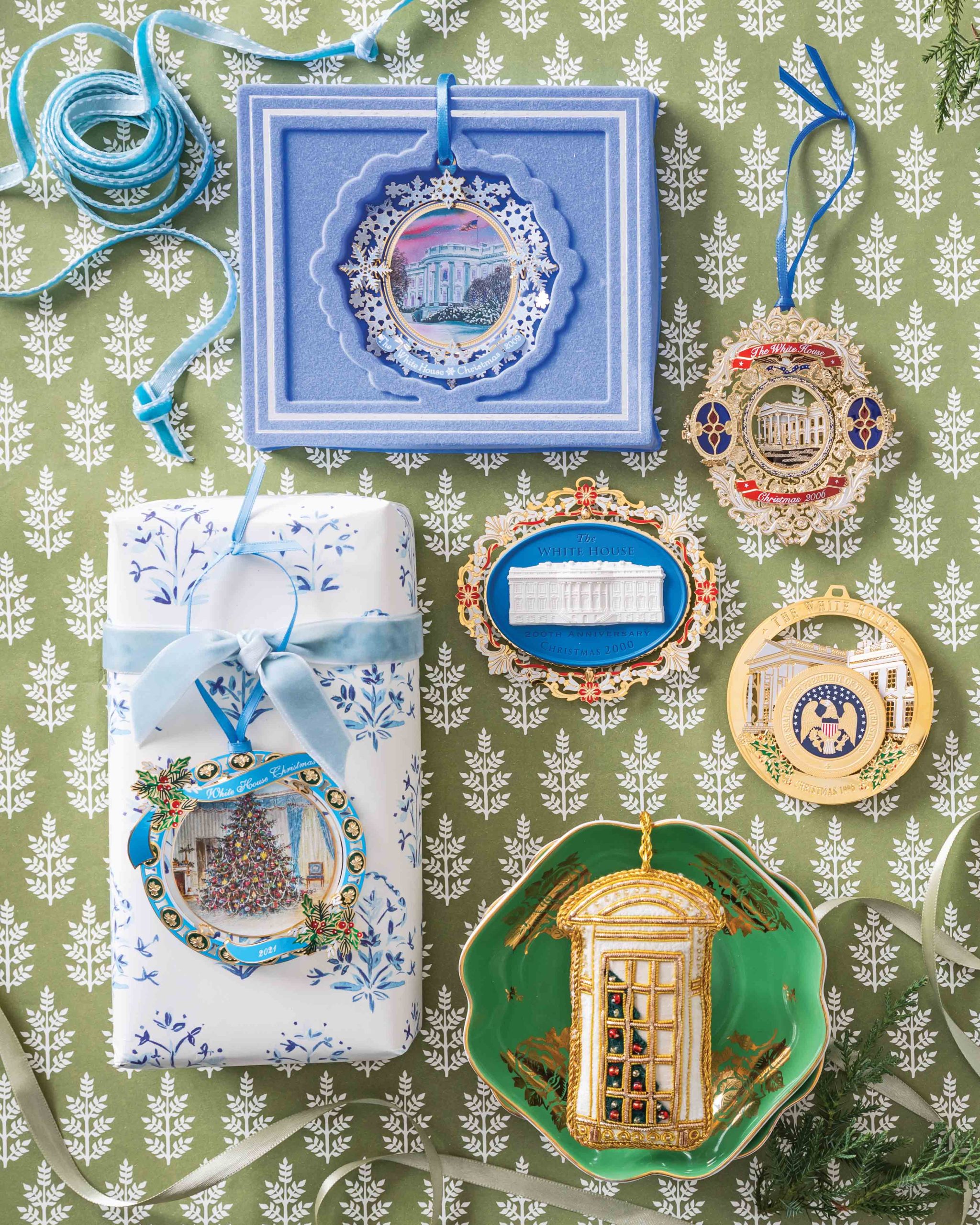 Set against a green and white pattern, a collection of detailed Christmas ornaments from The White House Historical Association is displayed.