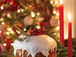 The focal point of a Christmas scene is panettone topped with homemade glaze, bright red berries, and sprigs of greenery.