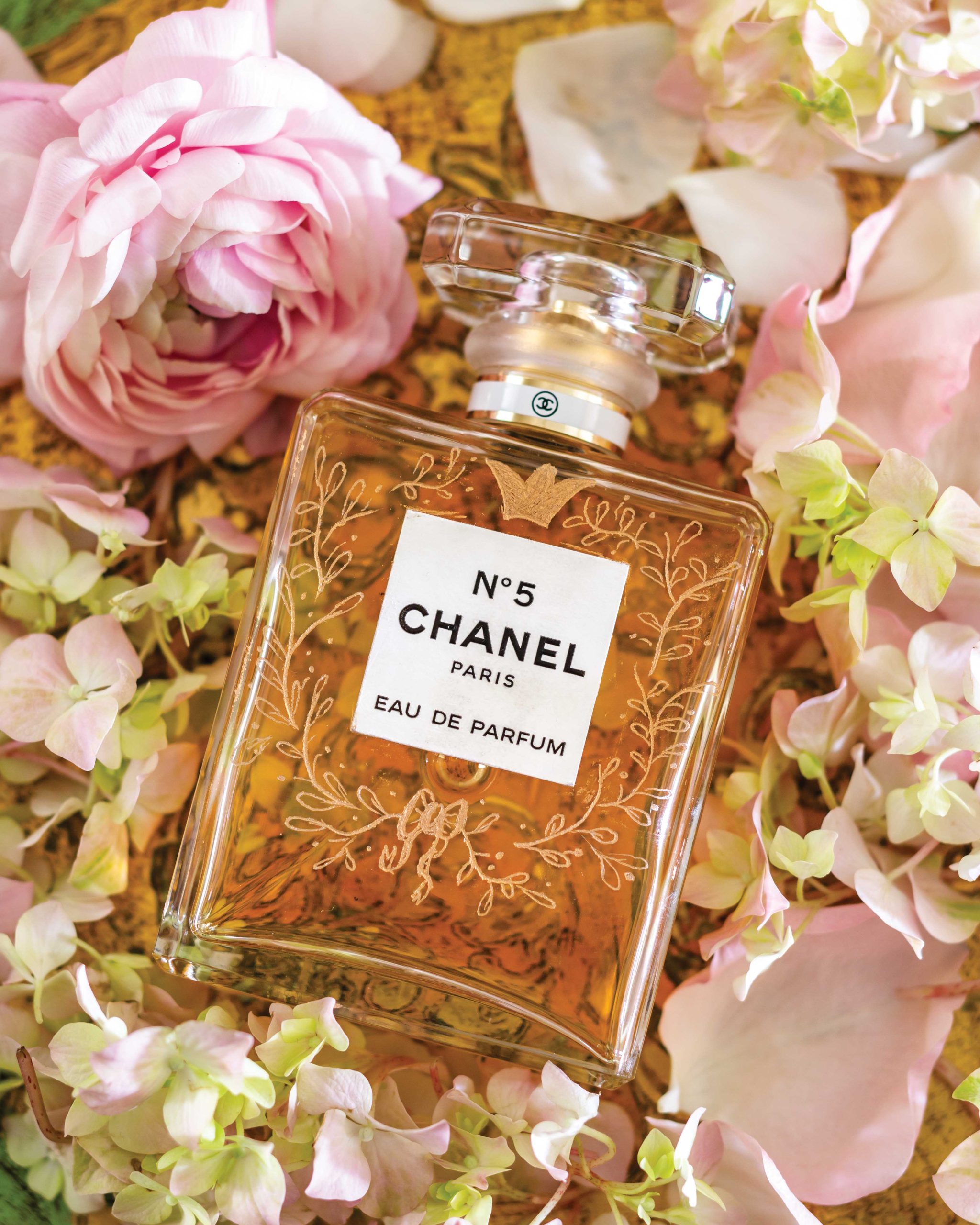 Surrounded by romantic blossoms, a bottle of Chanel No. 5 perfume has been engraved with laurel leaves and ribbon motifs.