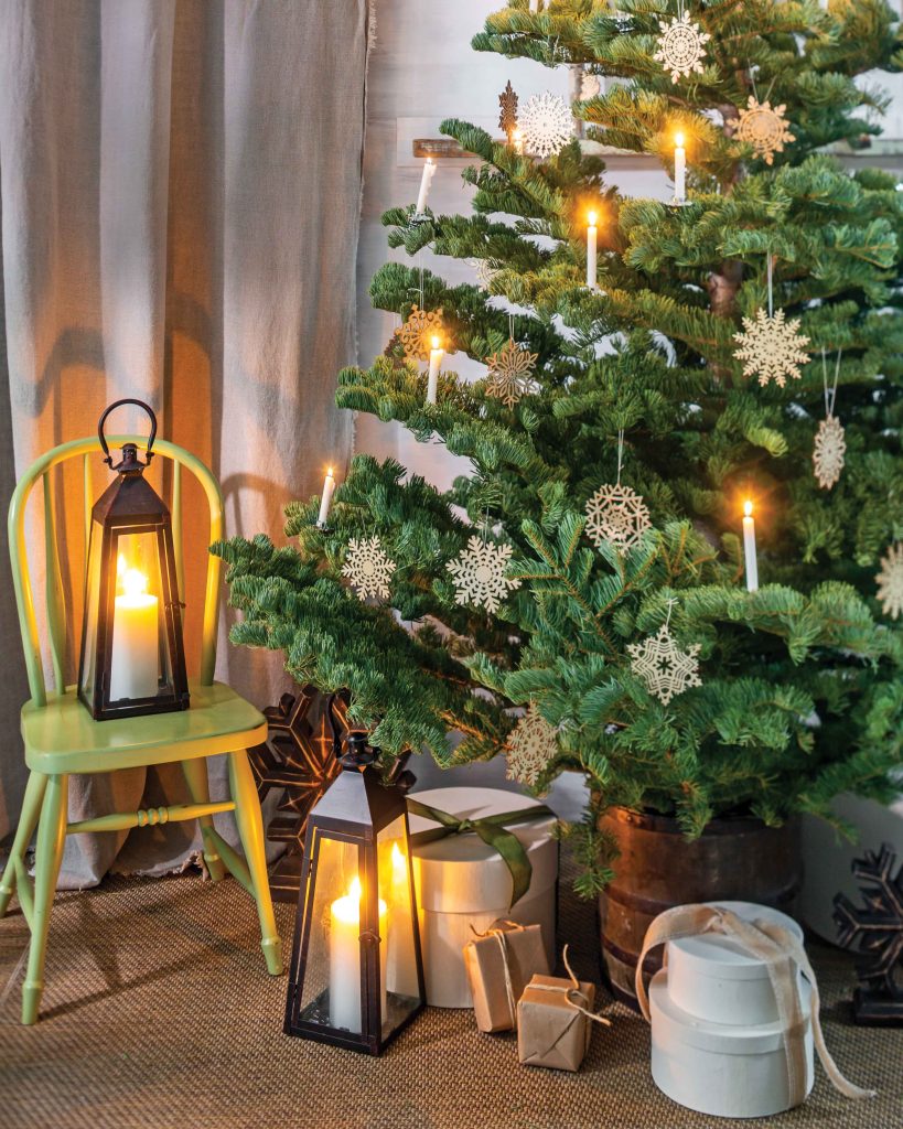 With simplicity and neutral tones, this Christmas tree is dressed in simple wooden snowflake ornaments and real candles. A lantern sits alongside the gifts at its base.