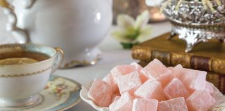 A bowl of Turkish Delight sits beside a cup of tea.