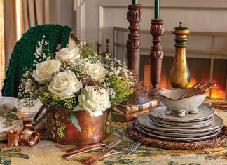 A stack of rustic plates, time-worn candlesticks, and a cache of snowy rosebuds dress the table in coziness.