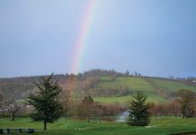 A rainbow shines above the verdant hills of Ireland.