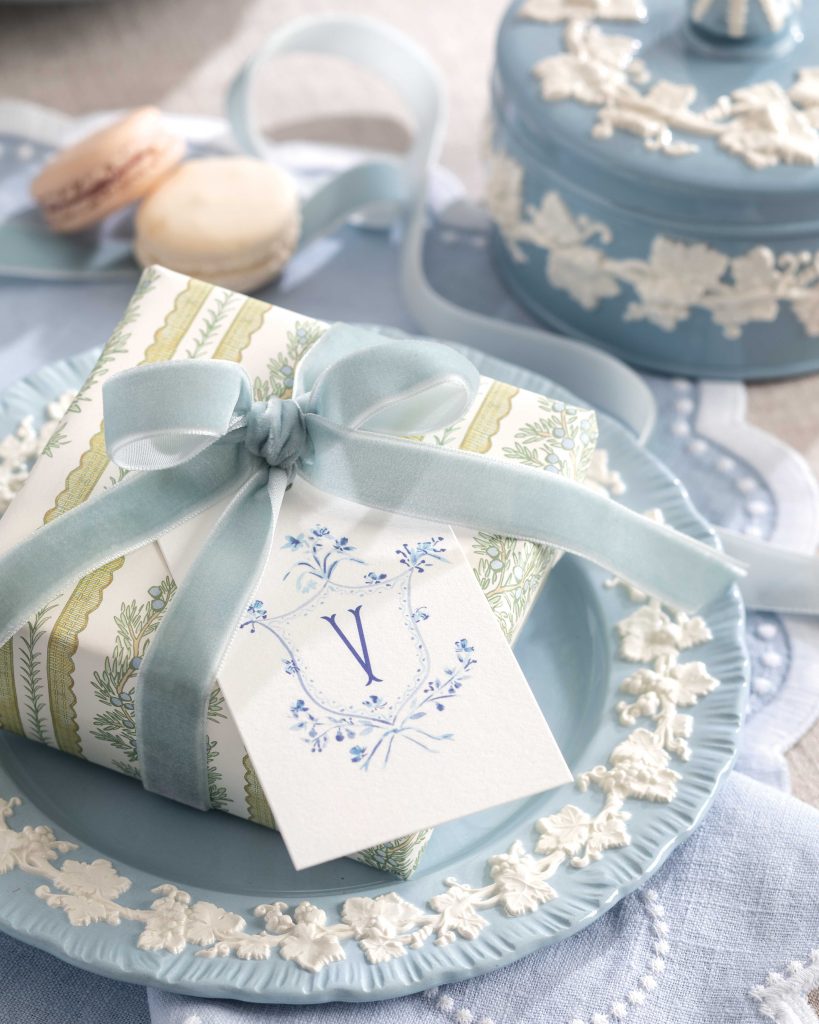A solitary blue-and-white Wedgwood Queen’s Ware plate and coordinating linens serve as a stage for a charming gift wrapped in blue ribbon.