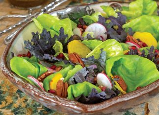 Bright green lettuce sits mingled with winter vegetables in a rustic bowl atop the table.