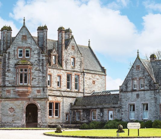 The stunning stone exterior of Castle Leslie is sandwiched between verdant Ireland countryside and a cerulean blue sky.