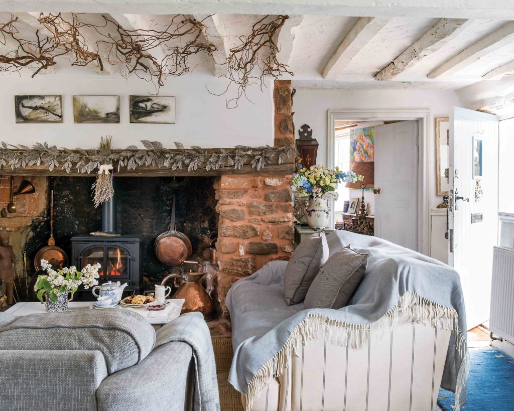 In the living room, bright ceilings and walls bring a vibrance to the home, while soft blue blankets draped over the sofa add a cozy feel that matches the atmosphere brought by the wood stove in the hearth.